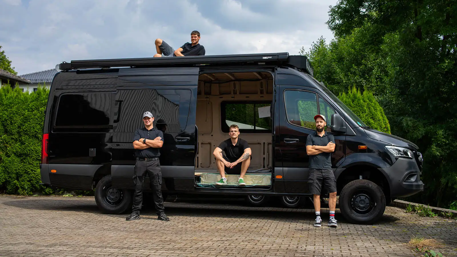 BIRDBUS Team vor einem schwarzen Campervan bei der Ausbau-Beratung