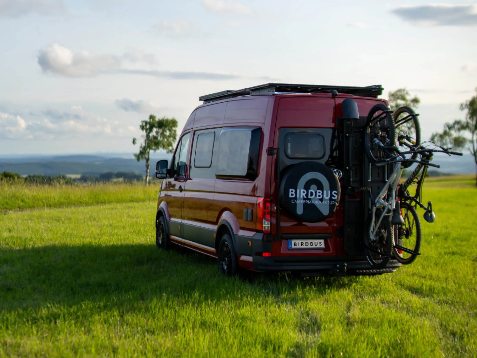 Heckansicht des roten VW Crafter Andy mit Fahrradträger und Camper-Ausbau