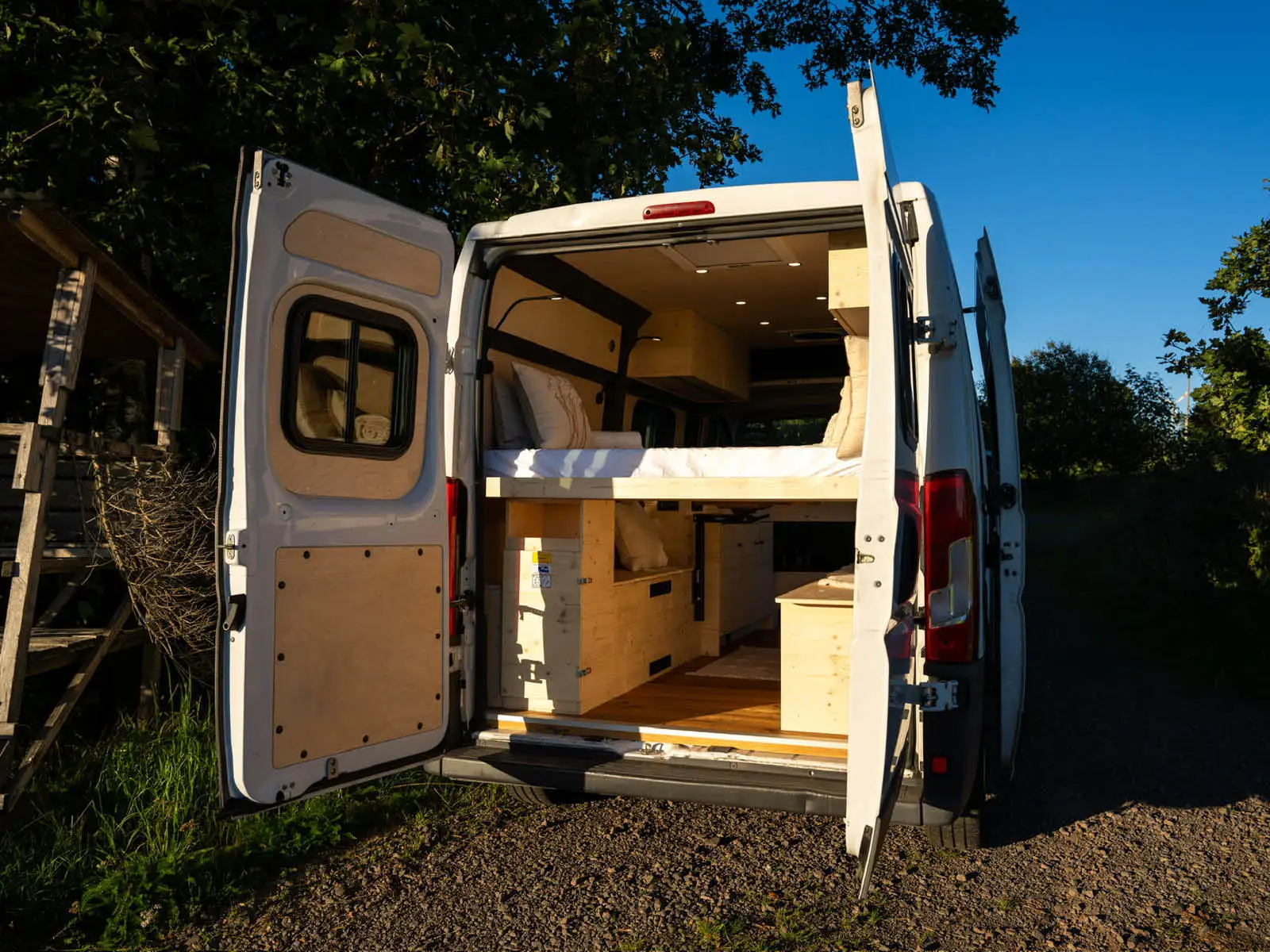 Geöffneter Fiat Ducato Karin mit hellem Camper-Ausbau im Grünen
