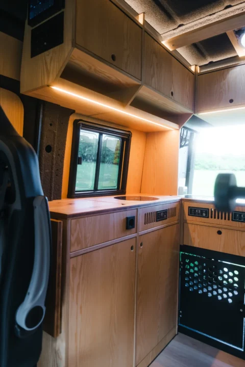 Warmer Holzinnenraum mit Küche im MAN-Trailer Campervan