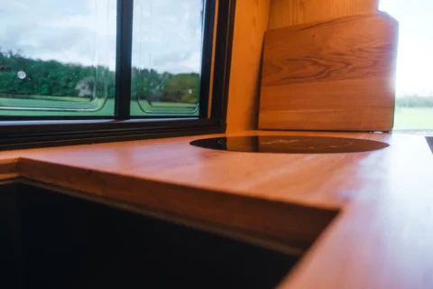 Induktionskochfeld und Holzarbeitsfläche im MAN-Trailer Campervan