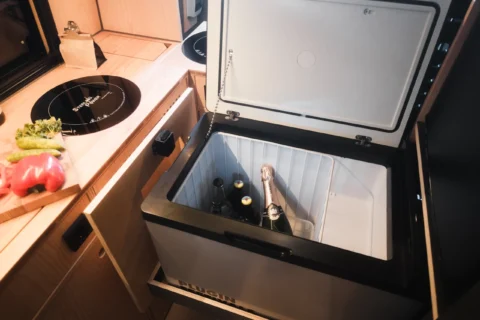 Geöffnete Kühlbox im Küchenmodul des MAN-Trailer Campervans