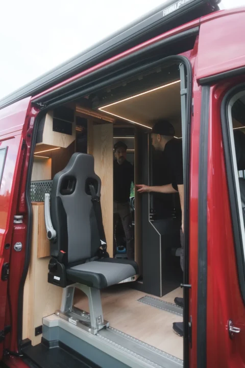 Sitzplatz und Schiebetür im roten MAN-Trailer Campervan