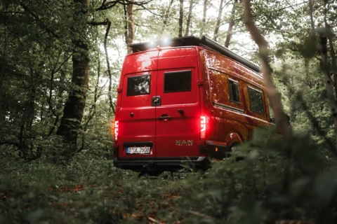 Roter MAN-Trailer Campervan von BIRDBUS im Wald