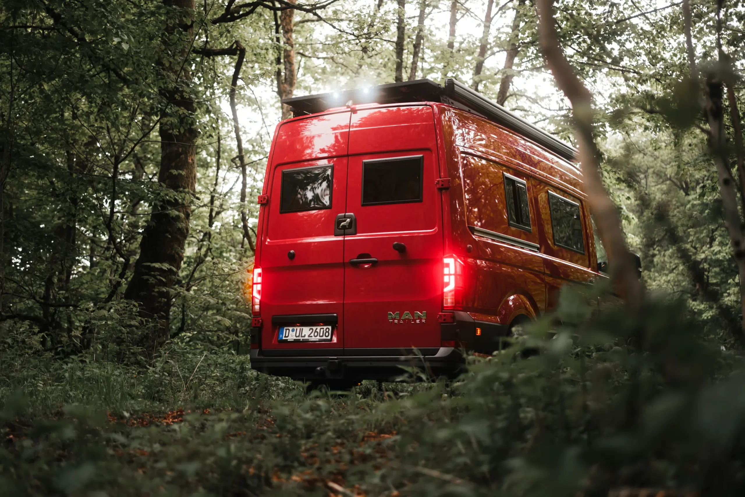 Roter MAN-Trailer Campervan von BIRDBUS im Wald