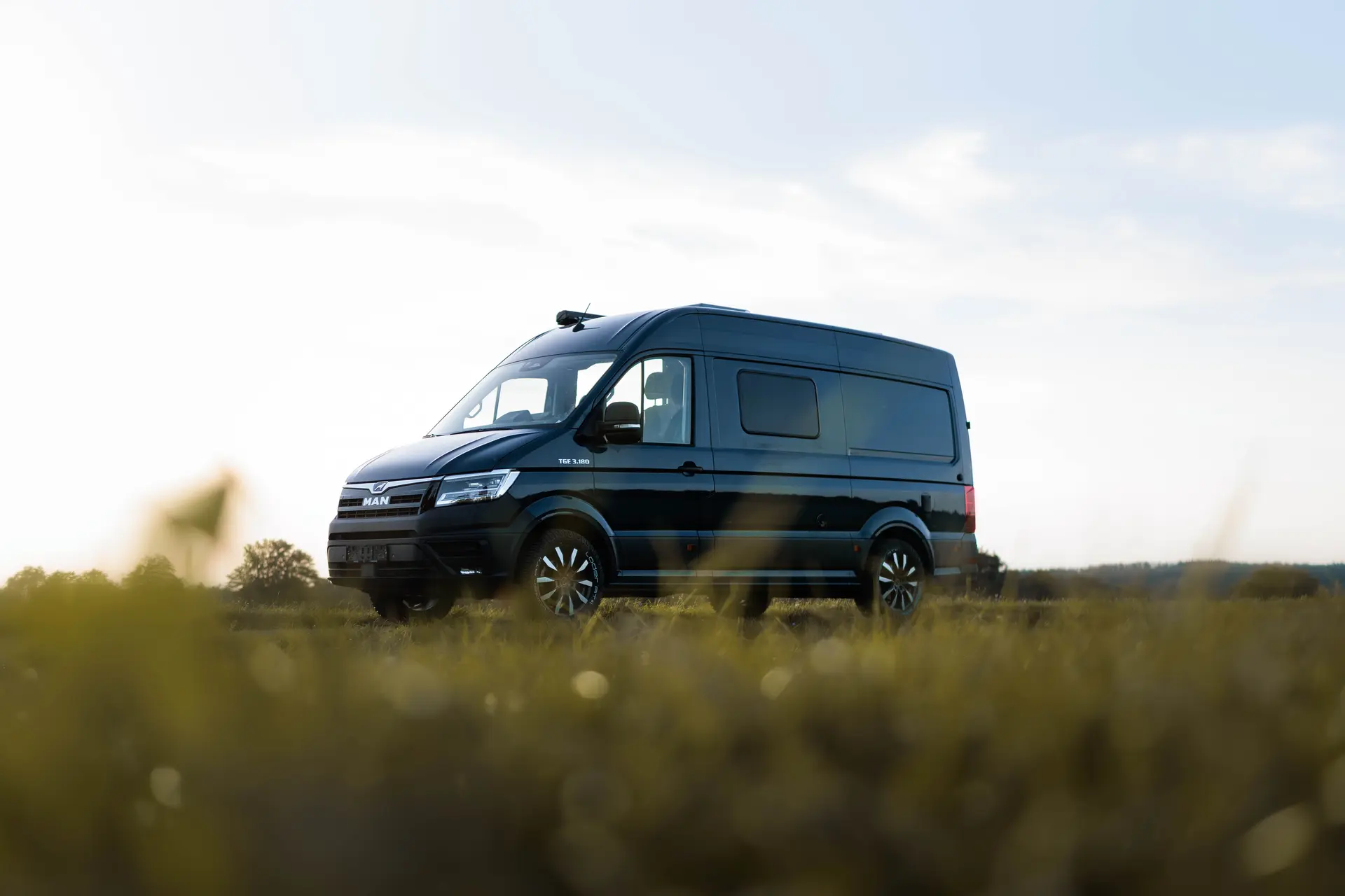 Blauer MAN TGE Campervan Blauer Klaus von BIRDBUS auf einer Wiese
